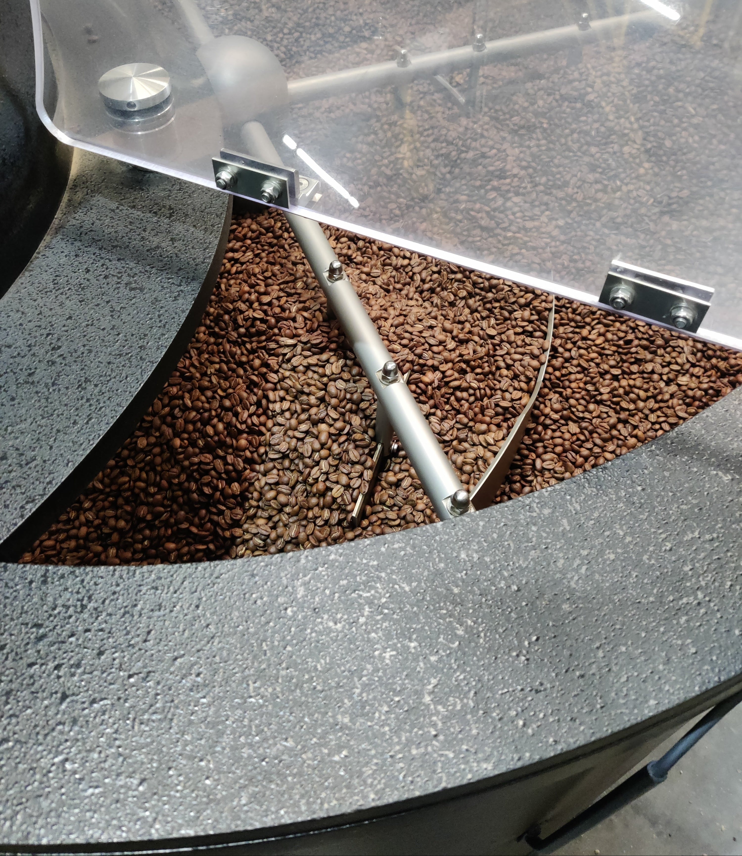 Coffee beans inside a coffee grinder with a clear container.